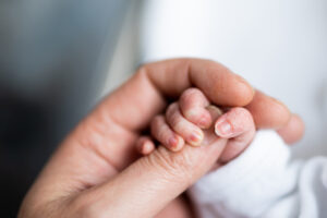hand of newborn baby who has just been born holding the finger of his father's hand