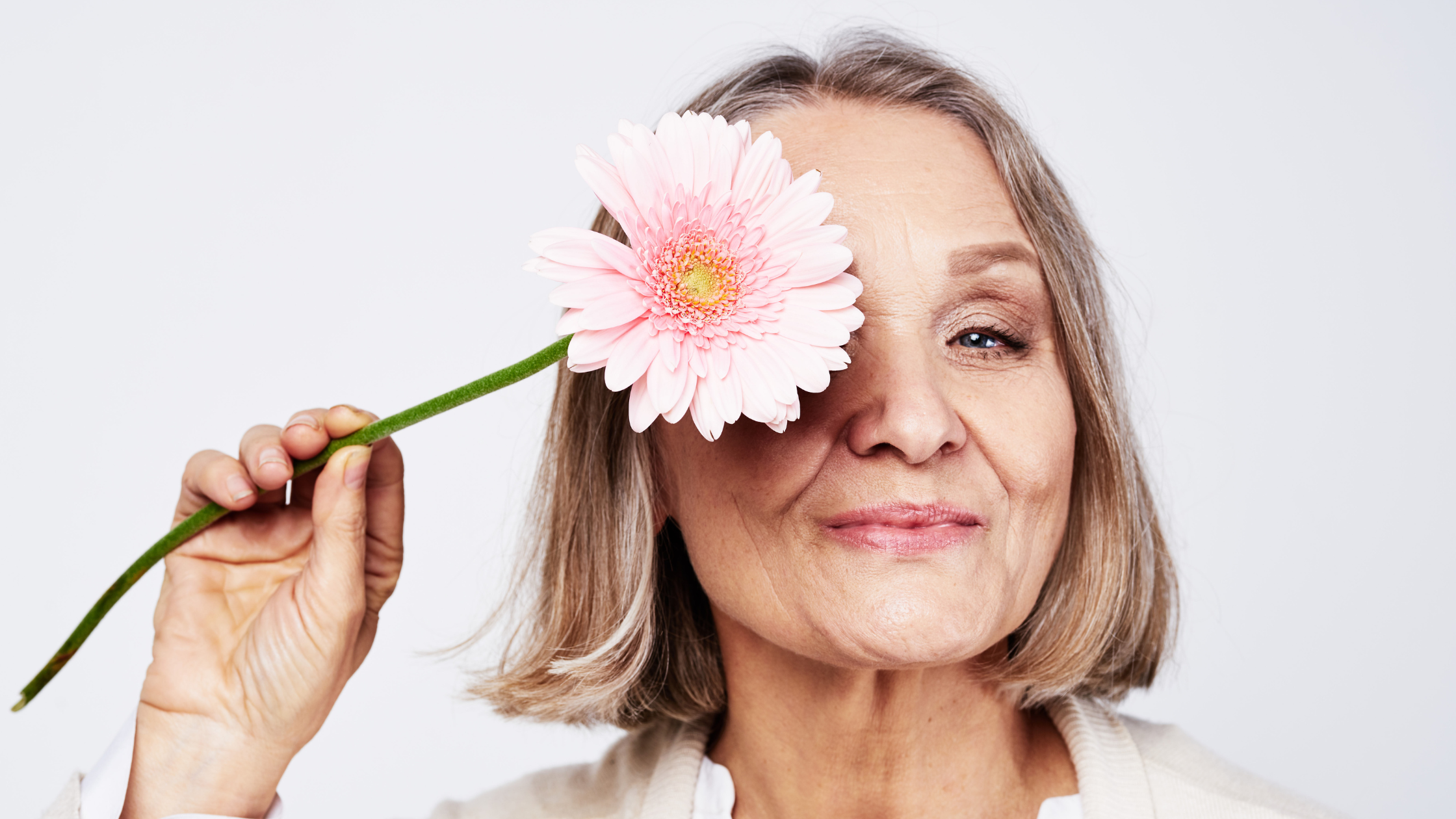 Older woman holding flower up to her face